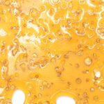 A vibrant close-up of El Jefe shatter, featuring a deep orange glossy color and a smooth, glass-like texture.