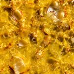 A close-up image of Khalifa Kush shatter, showcasing its translucent golden appearance and pure texture.