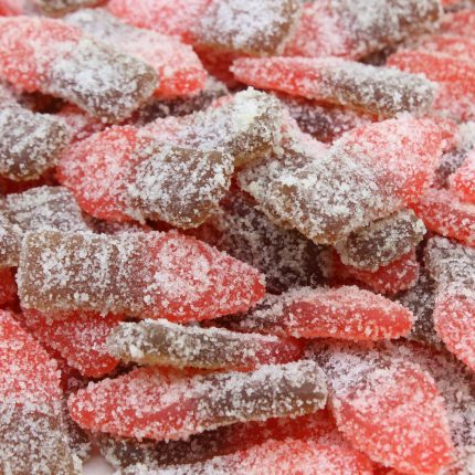 A close-up of Elevate Sour Cherry Bottles, cannabis-infused gummies shaped like mini soda bottles, with a vibrant red hue and a sugar-coated texture.